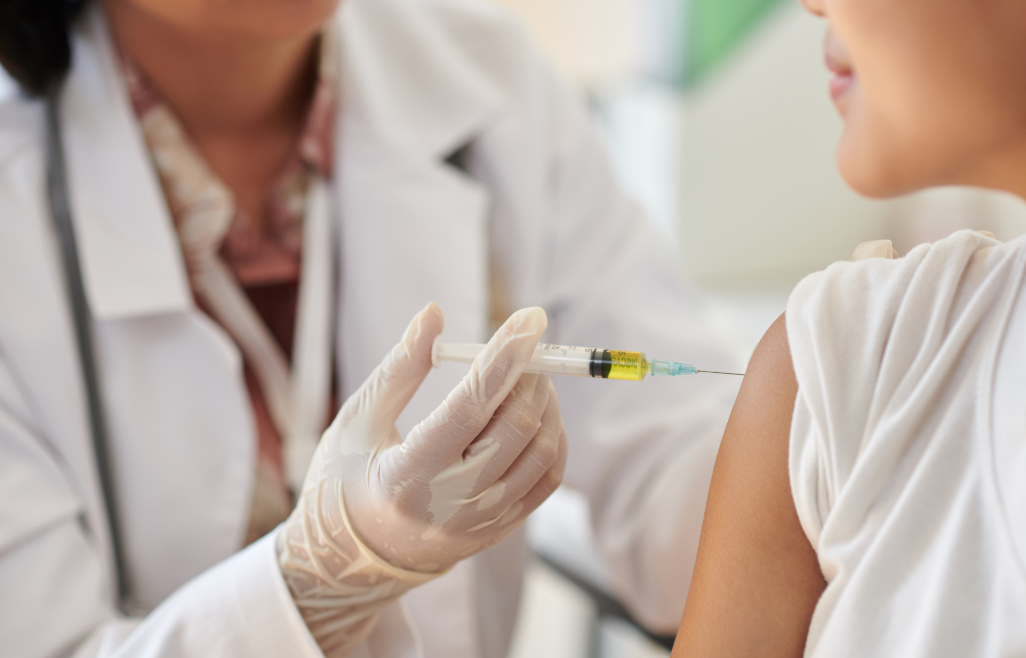 Lekarz podający kobiecie szczepionkę w ramię podczas wizyty medycznej.
