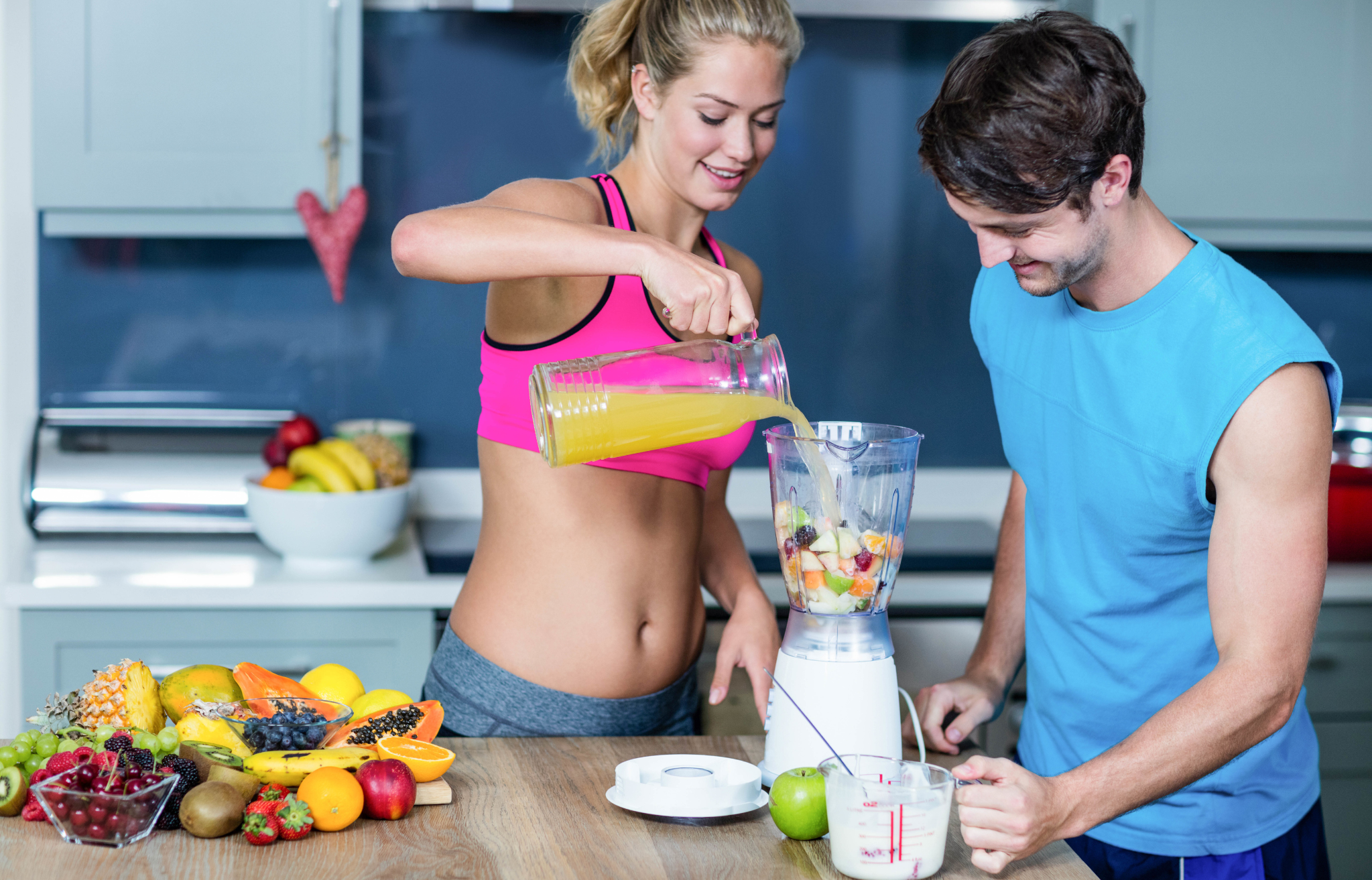 Para przygotowująca zdrowy koktajl z owoców w kuchni.
